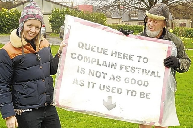 Michael and Emily Eavis holding queue here to complain banner